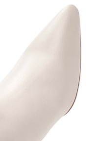 Zapato beige de punta, hecho de cuero suave, con una silueta elegante y una sutil textura brillante.