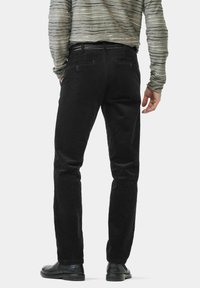 Schwarze Cordhosen mit strukturierter Oberfläche, schlanker Passform und zwei Gesäßtaschen, getragen mit einem grauen, gestreiften Langarmshirt.