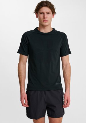 Zwarte sportieve t-shirt met korte mouwen, zachte textuur en subtiel logo detail op de zoom. Gecombineerd met zwarte shorts.