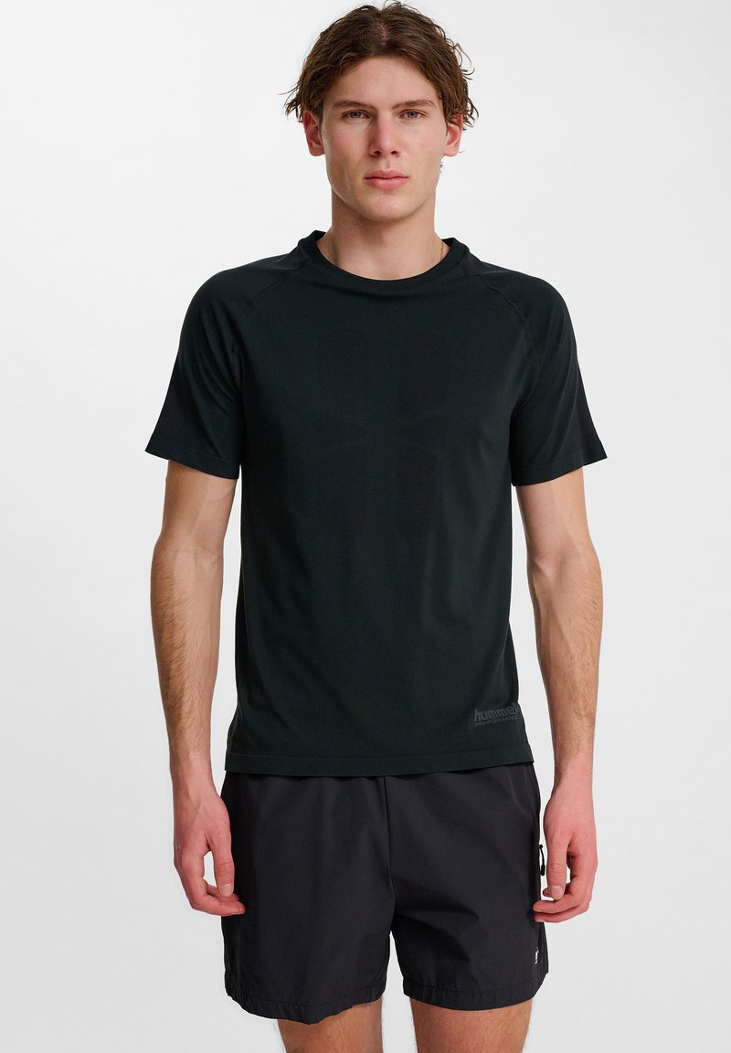 Zwarte sportieve t-shirt met korte mouwen, zachte textuur en subtiel logo detail op de zoom. Gecombineerd met zwarte shorts.