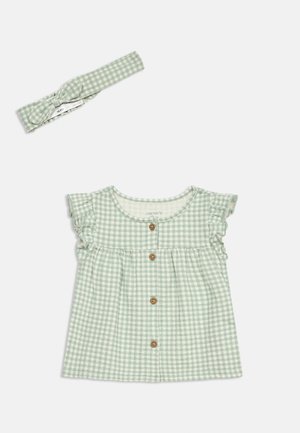 Hellgrünes und weiß kariertes Baby-Kleid mit Holzknöpfen und passendem geknotetem Stirnband vor weißem Hintergrund.