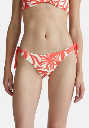 Bas de bikini rouge et blanc avec un motif floral, doté de liens sur les côtés et d'un design taille basse. Tissu lisse avec une finition légèrement brillante.