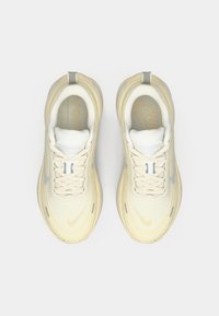 Μπεζ αθλητικά παπούτσια με διαπνέον επάνω μέρος από δίχτυ, στρογγυλή μύτη και μαλακό κολάρο. Διαθέτουν γκρίζες λεπτομέρειες και κορδόνια, με διακριτική επωνυμία.