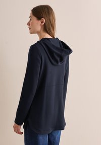 Navy hoodie with a relaxed fit, featuring long sleeves, a drawstring hood, and a curved hem. Smooth texture, simple design, and no visible patterns.