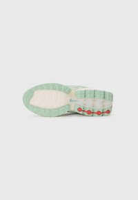 Schuhsohle mit einer hellgrünen Gummibasis, roten kreisförmigen Akzenten, geriffelter Textur und einer weißen Zwischensohle mit gemusterter Oberfläche.