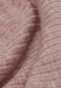 Vävd tyg i ljusrosa, med fina diagonala ränder och en strukturerad yta, som visar mjuka, ömtåliga fibrer.