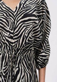 Sukienka w wzór zebry w czerni i kremie, z dekoltem w serek, bufkami oraz marszczoną talią z regulowanym sznurkiem.