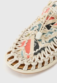 Sandal in tela con un motivo geometrico multicolore, lacci elastici bianchi, soletta in sughero e suola esterna texturizzata.