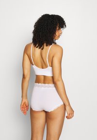Bralette in cotone rosa chiaro con spalline regolabili e una texture liscia, abbinato a slip a vita alta con bordo in pizzo in vita.