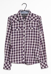Camicia a maniche lunghe a quadri nei colori navy, rosso e bianco. Presenta due tasche frontali, bottoni in perla e un colletto a punta. Appesa a un gancio.
