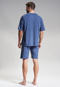 Conjunto de loungewear de algodón azul que incluye una camiseta de manga corta y pantalones cortos hasta la rodilla, con un corte relajado y una textura suave. Diseño liso.