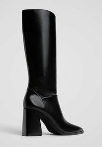 Bottine noire en cuir, montant jusqu'au genou, avec un bout carré, un talon épais et une texture lisse. Design minimaliste, sans quincaillerie ni motifs visibles.