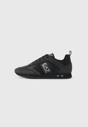 Zapatilla negra de corte bajo con paneles de malla y sintéticos, con cordones y logo EA7 Emporio Armani en el lateral y la suela, sobre fondo liso gris claro.