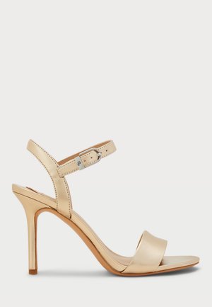 Beige high-heeled sandal with ankle strap and silver buckle, open toe, and slim stiletto heel on a white background.