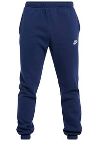 Mörkblå joggingbyxor i blandad bomullstyg, med elastisk midja, muddar och en vit Nike-logga på vänster lår.