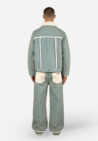 Ανοιχτό μπλε σακάκι με μοτίβο και κολάρο από κρέμα τεχνητή γούνα, συνοδευόμενο από παντελόνι σε ίδιο χρώμα. Διαθέτει υφασμάτινη υφή και αντίθετα λεπτομέρειες στις τσέπες.