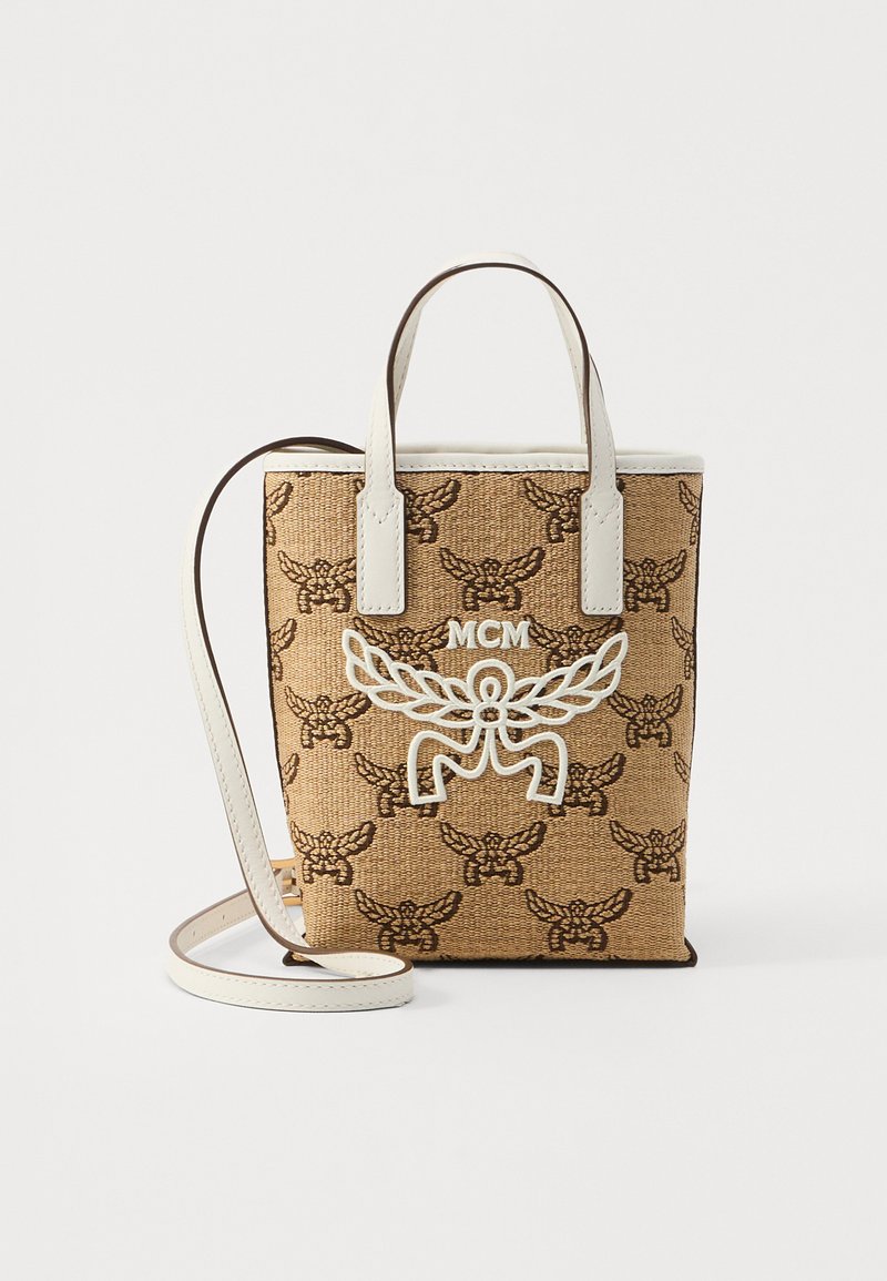 Pruun kudumisnuga, millel on detailne muster; valged nahast aksessuaarid; MCM logo valgena; lühikesed sangad ja eemaldatav õlarihm.