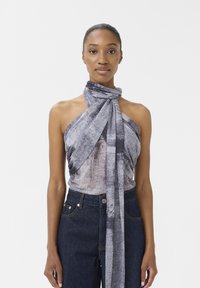 Grå omslagstopp med en strukturerad tyg med ett diagonalt mönster, knuten vid halsen; kombineras med högmidjade mörka jeans.