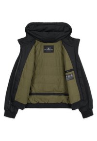 Veste noire ouverte pour montrer la doublure matelassée vert olive avec étiquette de la marque et étiquettes d'entretien à l'intérieur et une capuche en haut.