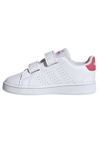 Baskets synthétiques blanches avec deux bandes auto-agrippantes, design perforé sur les côtés et un accent rose au niveau du talon. Semelle texturée.