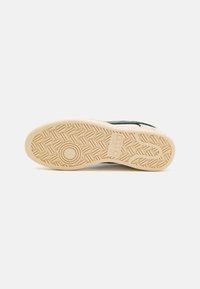Sneaker med svart overdel, hvite detaljer og en såle av gummigummi med et teksturert mønster for grep og holdbarhet.
