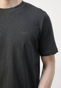 Camiseta de manga corta de color gris oscuro, fabricada en algodón suave, con un logo de marca sutil en el pecho. Diseño de cuello redondo con un corte cómodo.