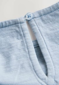Tissu tricoté bleu clair avec un petit bouton rond fermant une fente verticale étroite près d'un col ou d'un bord de manchette.