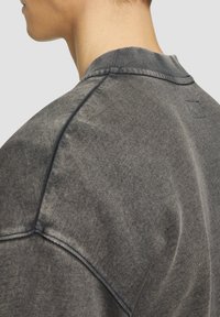 Dunkelgrauer, Rundhals-Sweatshirt mit leicht gebürsteter Textur, ausgestattet mit einem kleinen Logotag am hinteren Halsausschnitt und gerippten Bündchen.