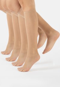 Collant beige al ginocchio realizzati in materiale trasparente, caratterizzati da una superficie liscia e da un semplice elastico nella parte superiore. Quattro paia esposti.
