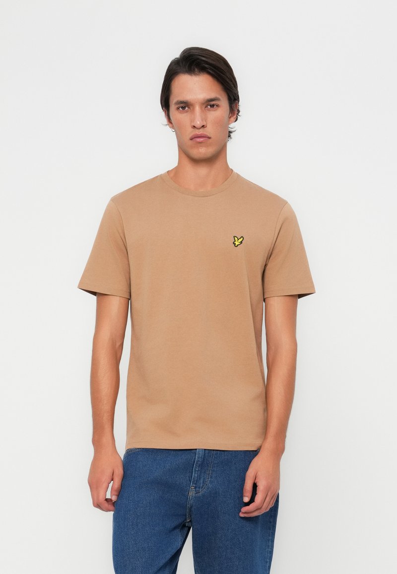 T-shirt court à manches courtes en coton, avec un petit logo de papillon jaune sur la poitrine gauche, col rond et coupe confortable.