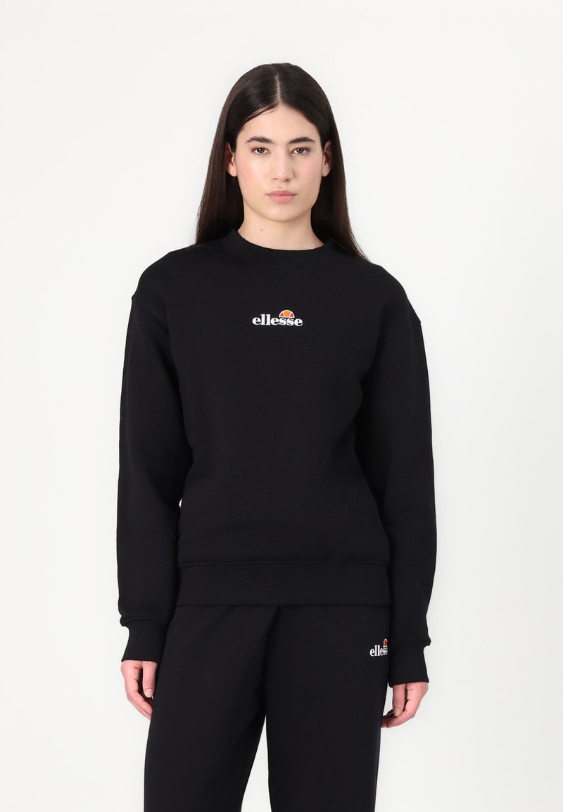 Svart sweatshirt med rund hals og ribbede mansjetter. Har en liten, fargerik "ellesse"-logo på brystet og matchende svarte bukser.