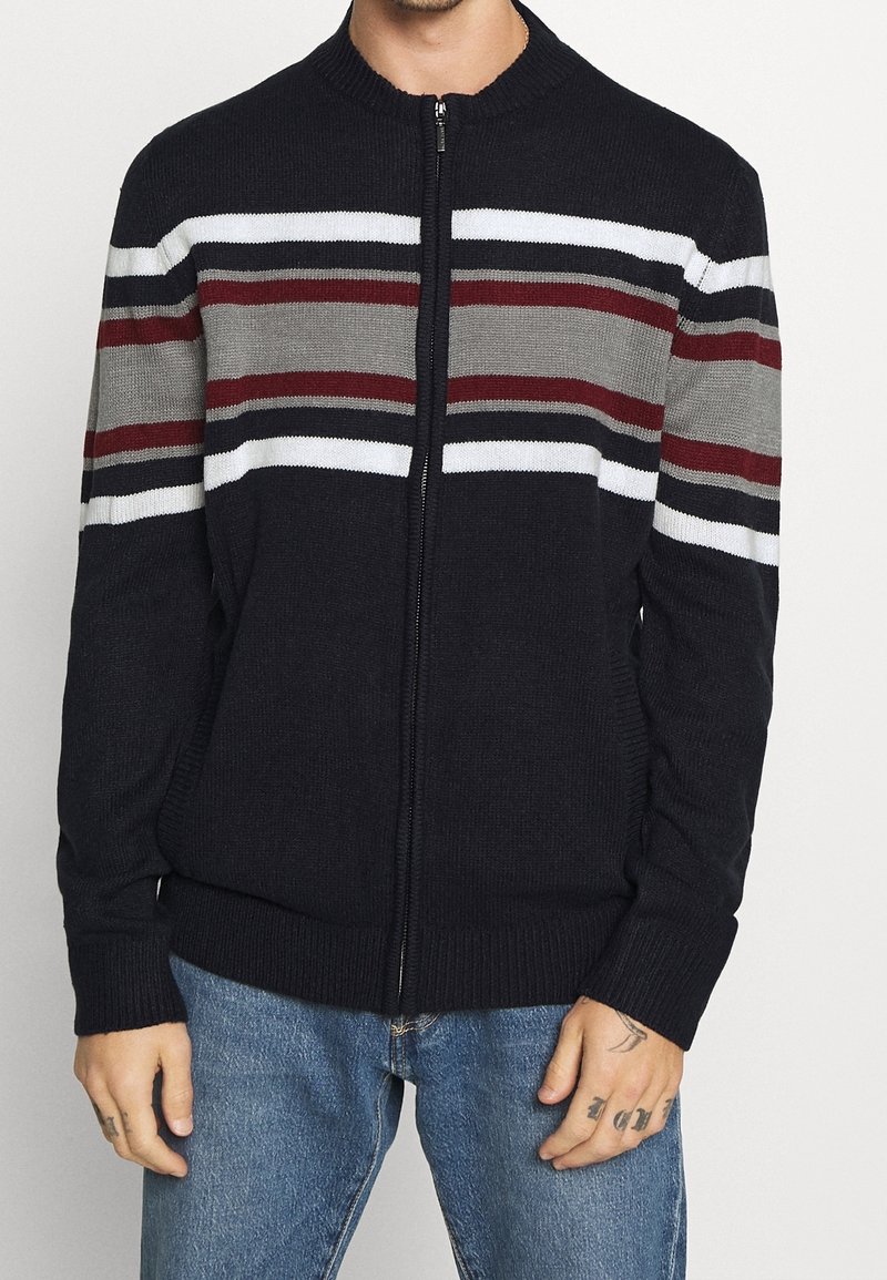 Cardigan zippé en tricot bleu marine, avec des rayures horizontales en gris, bordeaux et blanc. Poignets et ourlet en côte avec un design col rond.