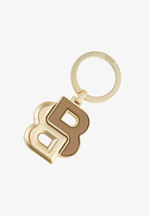 Porte-clés en or avec des lettres entrelacées "B" et "D" dans des couleurs contrastées, finition lisse et attache en anneau circulaire.