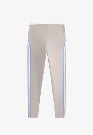 Lichtbeige sportleggings met blauwe en witte verticale strepen langs de buitenzijden, weergegeven tegen een witte achtergrond.