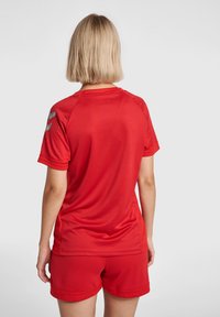 Rød sportsjersey med korte ærmer, der har en mesh-struktur. Inkluderer lysegrå accenter på skuldrene og en rund halsudskæring.