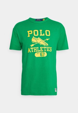 Camiseta de algodón verde con mangas cortas, cuenta con la impresión amarilla "POLO ATHLETICS NY 67" y gráficos de una zapatilla y flechas.