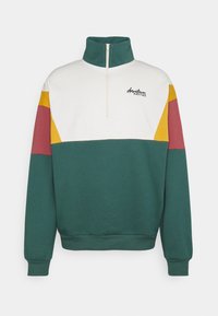 Felpa verde e bianca con mezza cerniera, caratterizzata da strisce color-block in rosso e giallo e un logo sul petto.