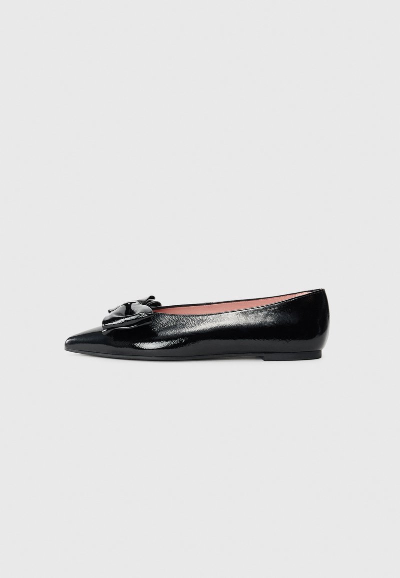 Ballerines en cuir verni noir avec un bout pointu et un nœud décoratif à l'avant, présentant une texture lisse et un design minimaliste.