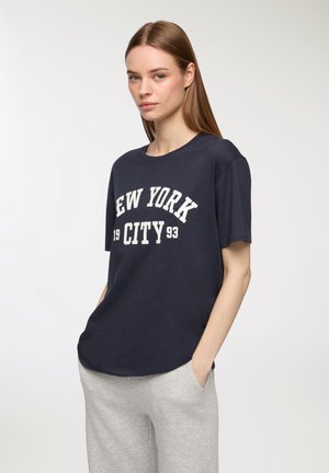 T-shirt in cotone blu navy con maniche corte. Presenta la scritta "NEW YORK CITY 1993" stampata in bianco. Collo arrotondato e vestibilità rilassata.