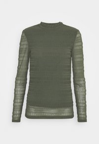 Maglietta a maniche lunghe in verde oliva scuro, con strisce orizzontali textured e collo alto, dotata di pannelli trasparenti sulle maniche.
