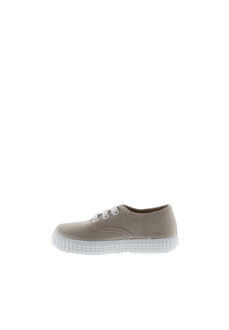 Zapatilla de lienzo beige con suela de goma blanca, puntera redonda y tres ojales. Presenta un detalle de costura sutil en los lados. Diseño compacto.