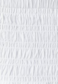 Witte stof met horizontale rijen van geplooide, gestructureerde stiksels, die een gerimpeld effect creëren. Gladde oppervlakte, lichtgewicht materiaal.