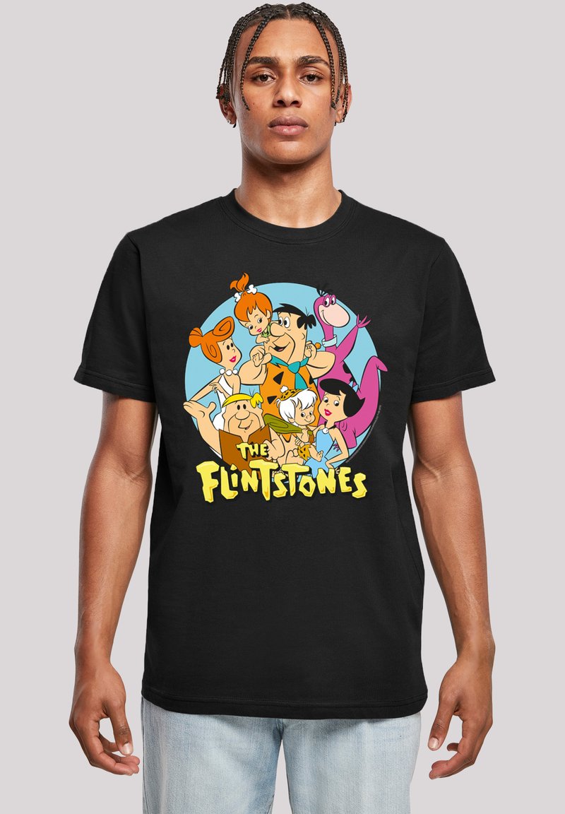 Melnā kokvilnas T-kreklā ir krāsains „Flinstoni” varoņu prints apļveida dizainā ar dzeltenu tekstu zem tā.