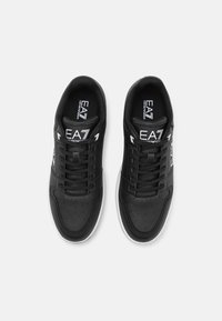 Sneaker nere con finitura in pelle liscia, dettagli perforati sulla punta, lacci simmetrici e suole in gomma bianca. Presentano il branding EA7.