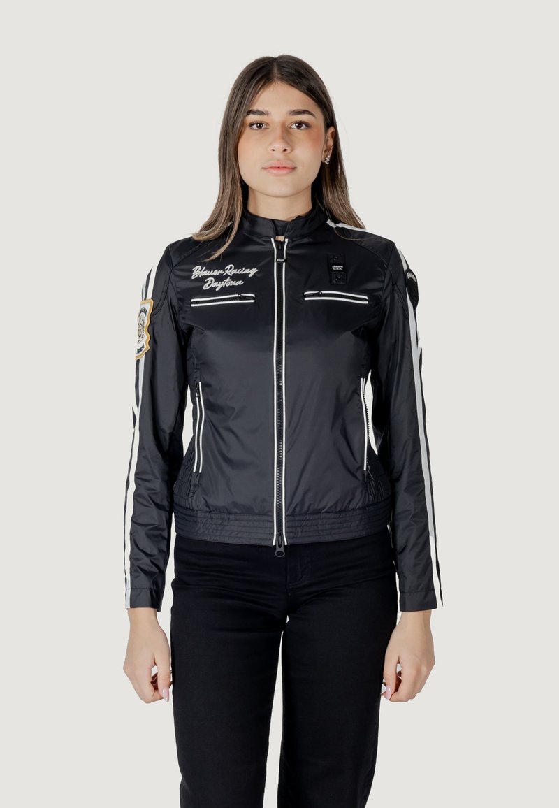 Giacca nera con zip, dotata di strisce bianche sulle maniche, loghi ricamati e due tasche anteriori con zip; materiale liscio e leggero.