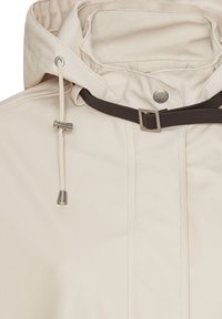 Impermeabile beige con cordino regolabile per il cappuccio e fibbia marrone scuro a tracolla nella zona del collo.