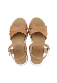 Sandalias de cuero marrón con tiras cruzadas sobre los dedos y correas en el tobillo con hebillas de metal, colocadas sobre plantillas beige y suelas blancas.