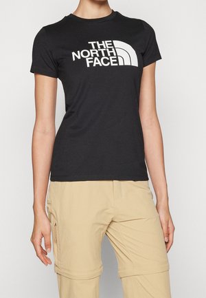 Person wearing black short-sleeve The North Face logo t-shirt and beige convertible cargo pants with zip-off legs.