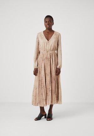 Flowy long dress in beige with an animal print, featuring a V-neck, long sleeves, and a gathered waist. Paired with black block-heeled mules.
