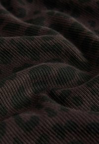 Mustmust tekstuuriga must kangas, millel on ribiline pind ja peene leopardimustri muster materjali voldides ja kõverates.